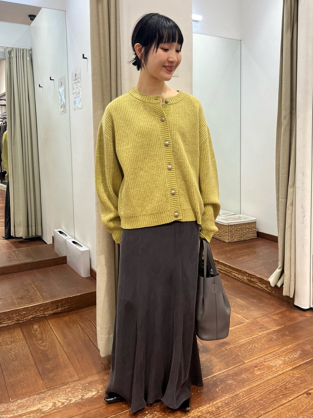 グレー系のトートバッグ、グレー系のスカート、ブラック系のパンプスを着用したレディースの秋コーディネートの2枚目の写真