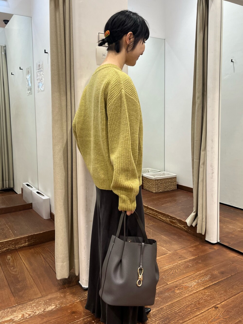 グレー系のトートバッグ、グレー系のスカート、ブラック系のパンプスを着用したレディースの秋コーディネートの4枚目の写真