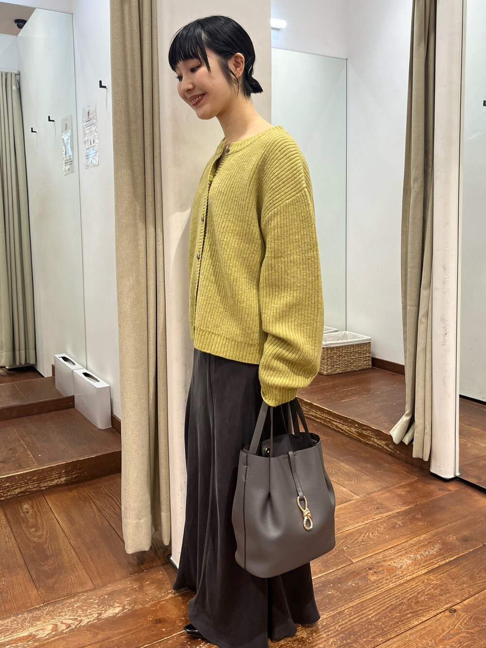 グレー系のトートバッグ、グレー系のスカート、ブラック系のパンプスを着用したレディースの秋コーディネートの6枚目の写真