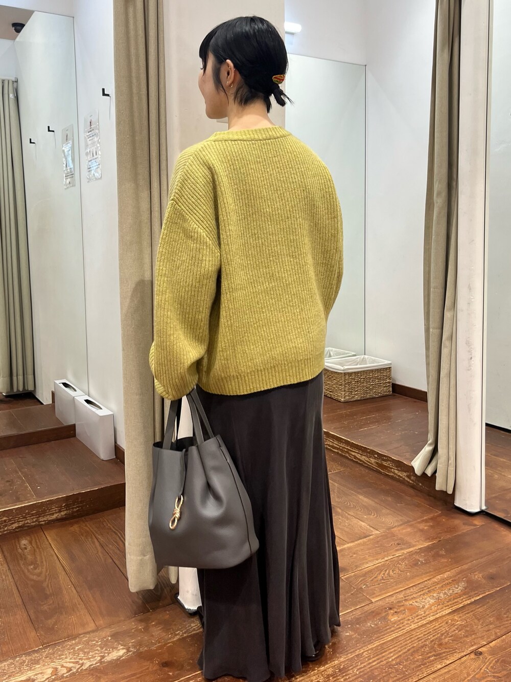 グレー系のトートバッグ、グレー系のスカート、ブラック系のパンプスを着用したレディースの秋コーディネートの5枚目の写真