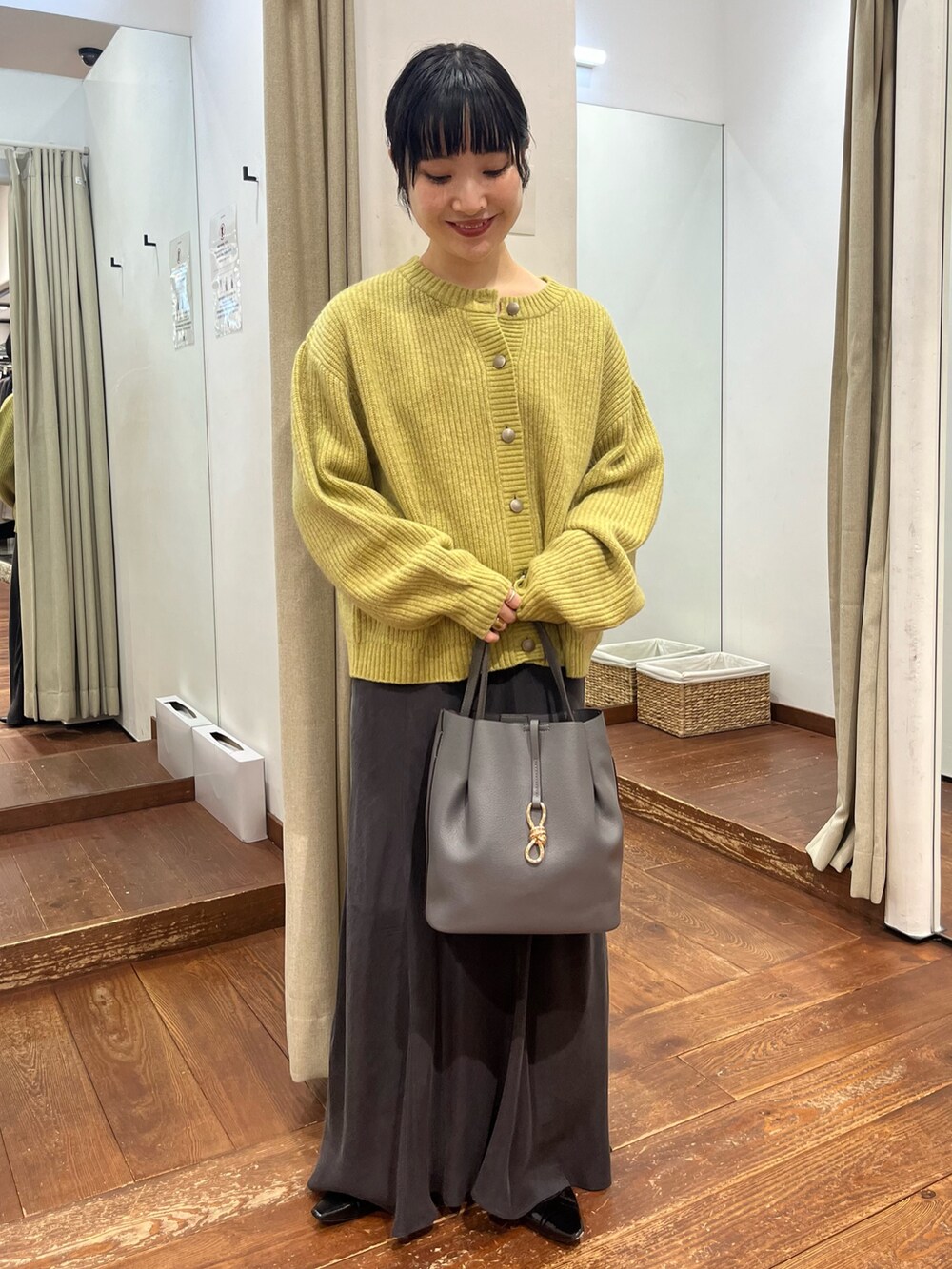 グレー系のトートバッグ、グレー系のスカート、ブラック系のパンプスを着用したレディースの秋コーディネートの3枚目の写真