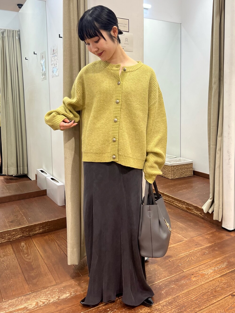 グレー系のトートバッグ、グレー系のスカート、ブラック系のパンプスを着用したレディースの秋コーディネートの7枚目の写真