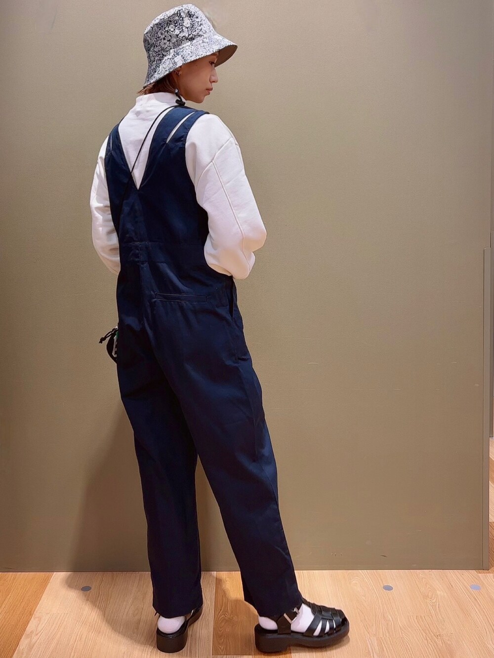 ホワイト系のスウェット、ブルー系のつなぎ/オールインワン、ブラック系のサンダルを着用したレディースの春コーディネートの3枚目の写真