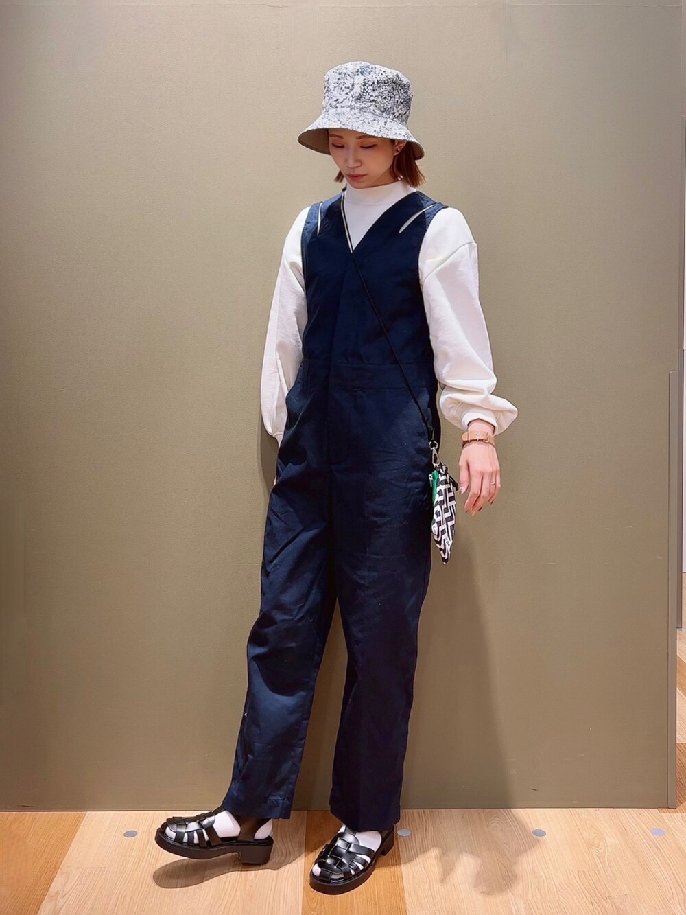 ホワイト系のスウェット、ブルー系のつなぎ/オールインワン、ブラック系のサンダルを着用したレディースの春コーディネートの2枚目の写真