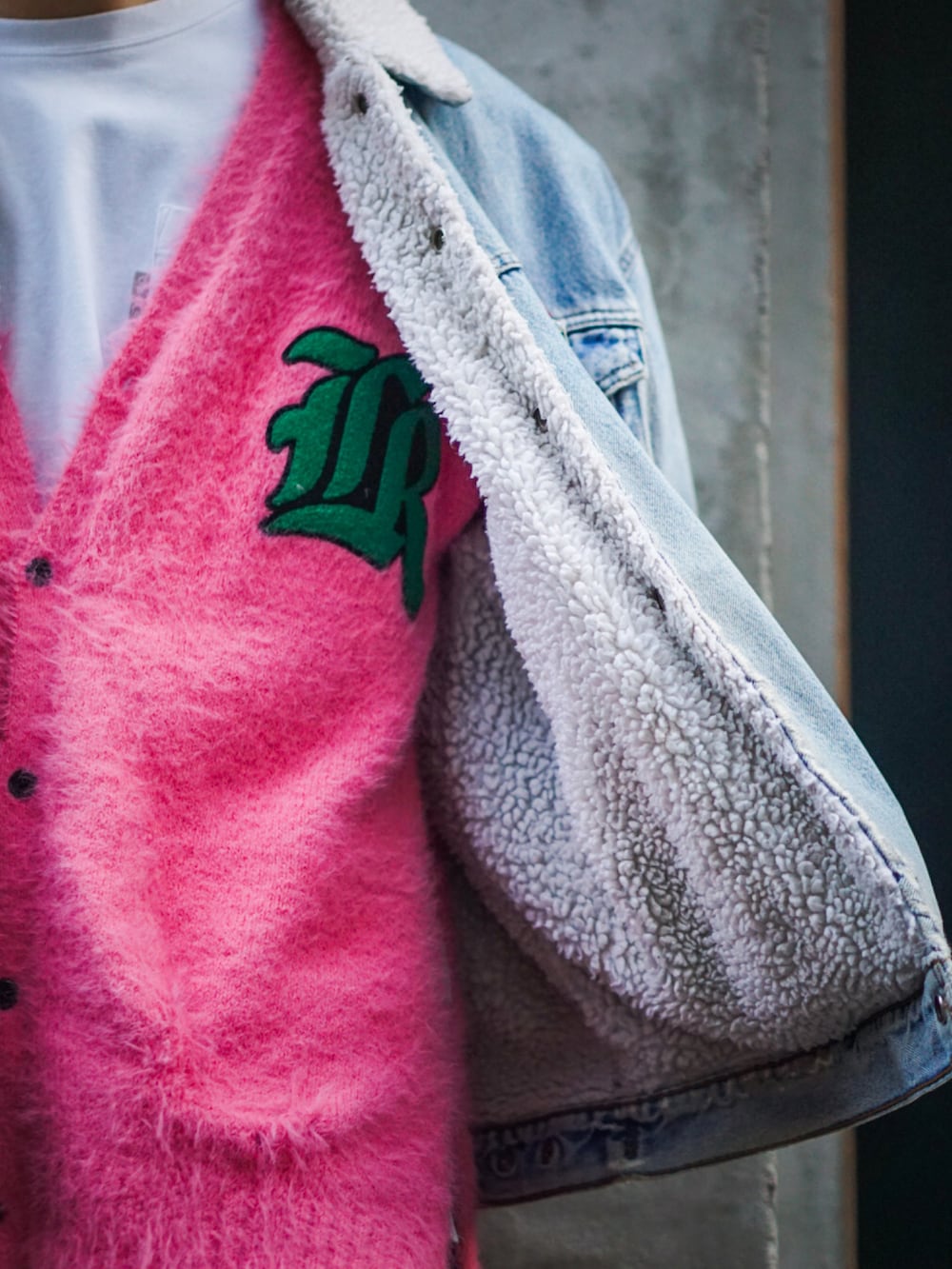 ブルー系のデニムジャケット、ピンク系のカーディガン/ボレロ、ブラック系のカーゴパンツを着用したメンズの冬コーディネートの3枚目の写真