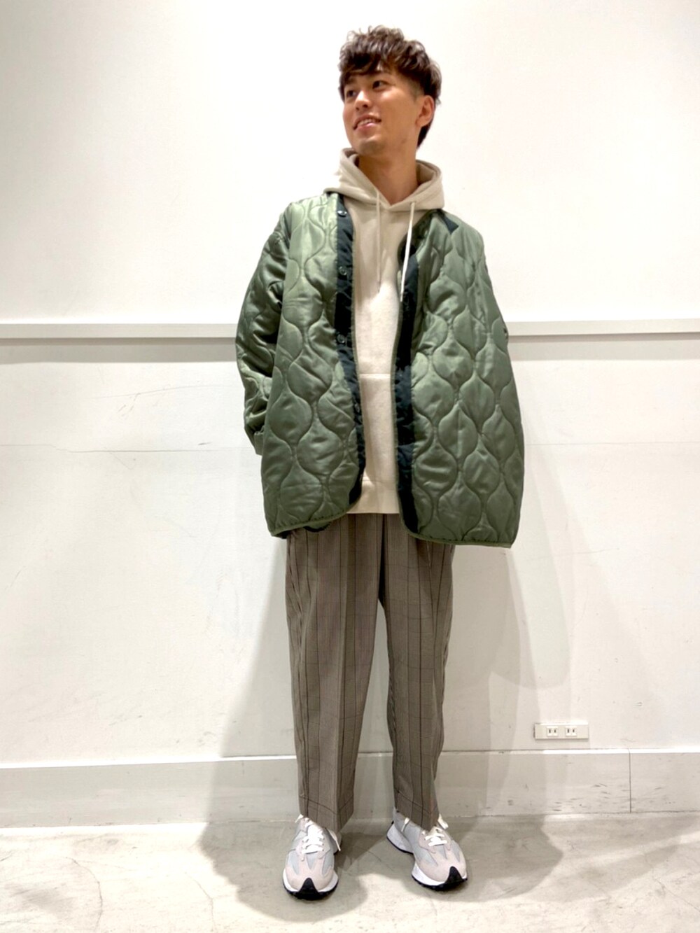 ベージュ系のスラックス、グレー系のスニーカー、グリーン系のモッズコートを着用したメンズの秋コーディネートの3枚目の写真