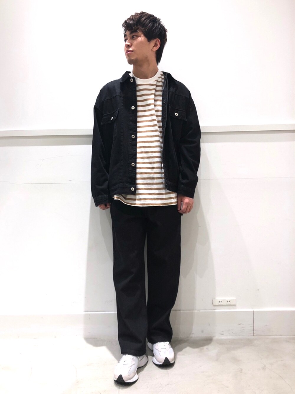 ベージュ系のTシャツ/カットソー、グレー系のスニーカー、ブラック系のデニムジャケットを着用したメンズの冬コーディネートの2枚目の写真