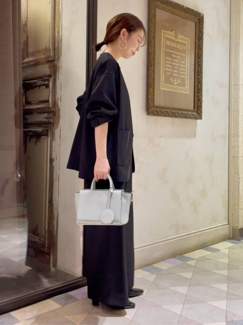 グリーン系のハンドバッグ、ブラック系のその他アウター、ブラック系のその他パンツを着用したレディースの冬コーディネートの4枚目の写真