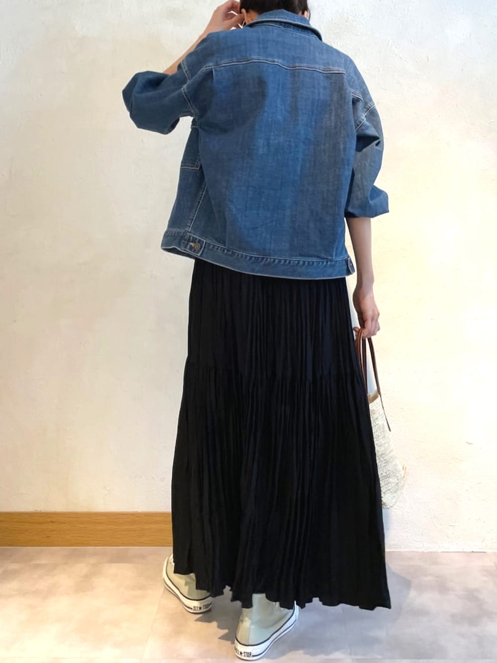 ブルー系のデニムジャケット、ブラック系のスカート、ホワイト系のかごバッグを着用したレディースの春コーディネートの3枚目の写真