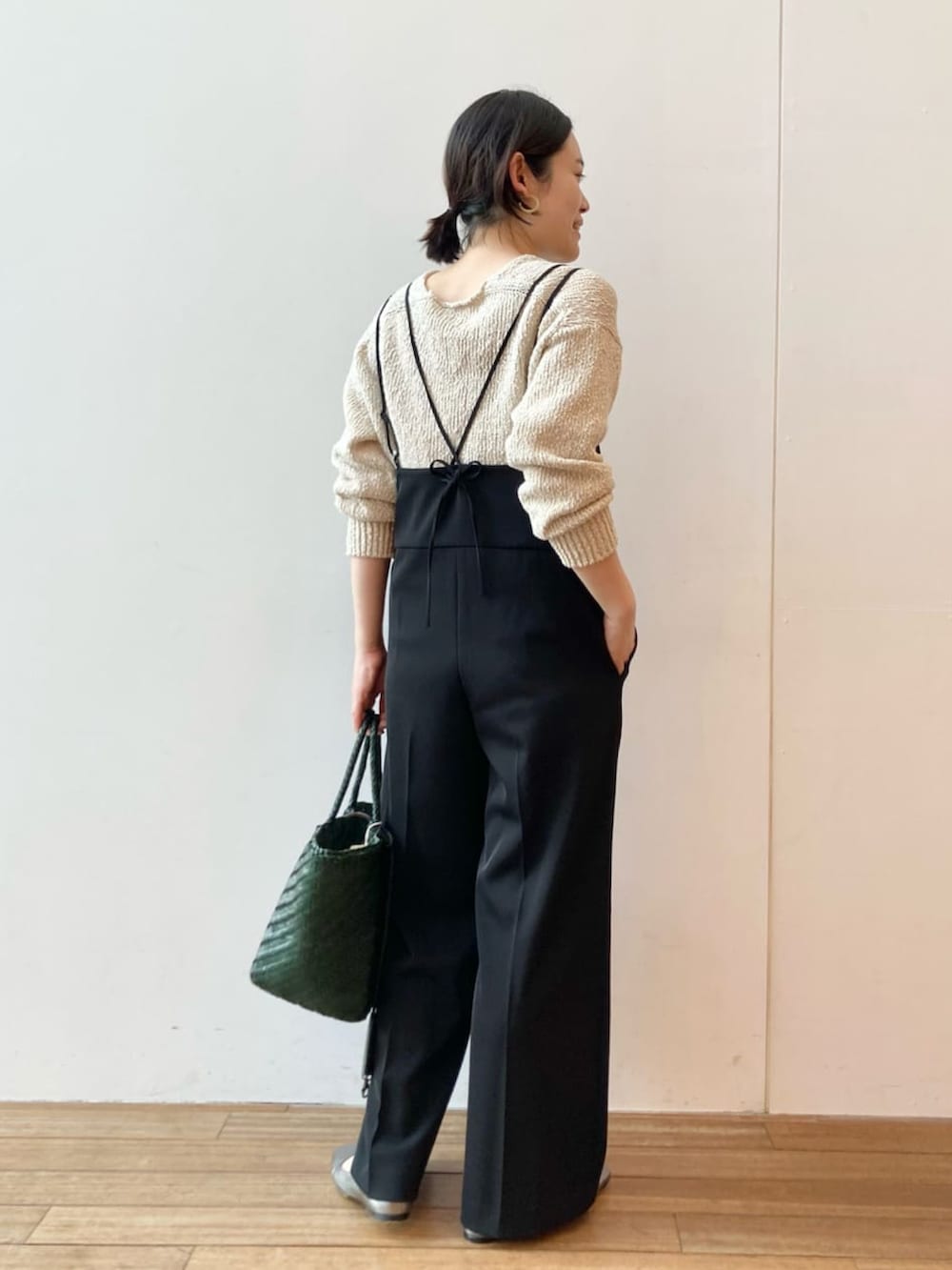 ベージュ系のニット/セーター、ブラック系のサロペット/オーバーオール、グリーン系のトートバッグを着用したレディースの春コーディネートの2枚目の写真