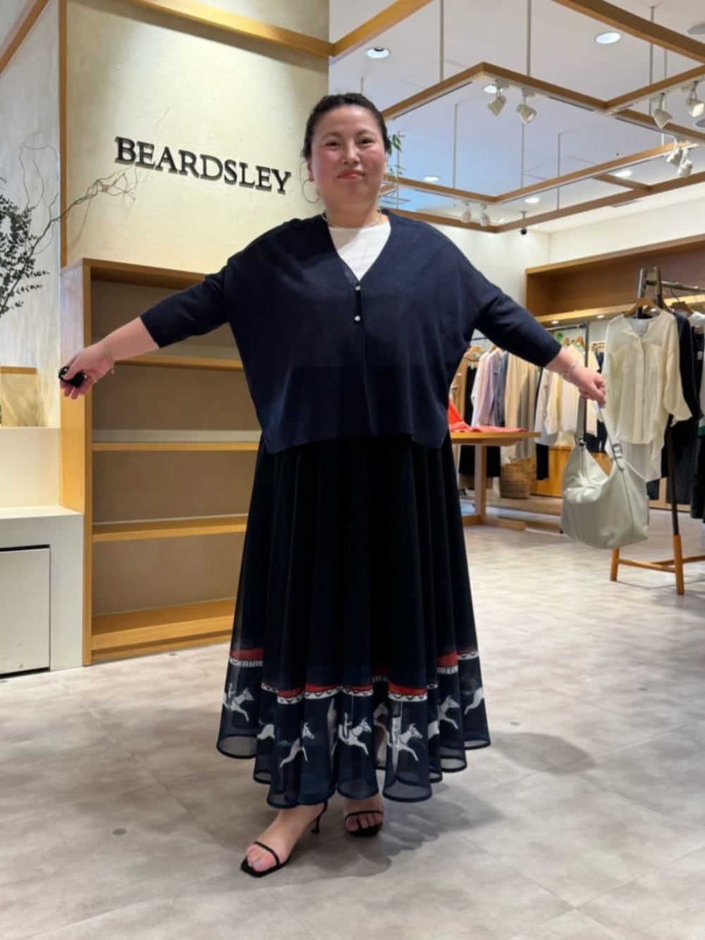 ホワイト系のトートバッグ、ブルー系のカーディガン/ボレロ、ブルー系のスカートを着用したレディースの春コーディネートの6枚目の写真