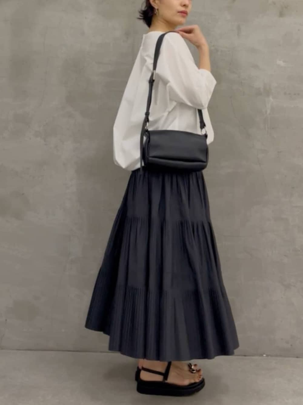 グレー系のスカート、ブラック系のショルダーバッグ、ホワイト系のシャツ/ブラウスを着用したレディースの春コーディネートの3枚目の写真