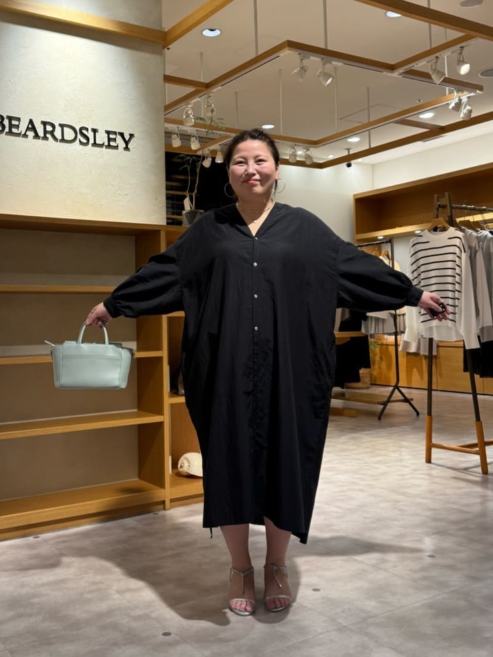 グリーン系のハンドバッグ、ブラック系のワンピースを着用したレディースの冬コーディネートの6枚目の写真