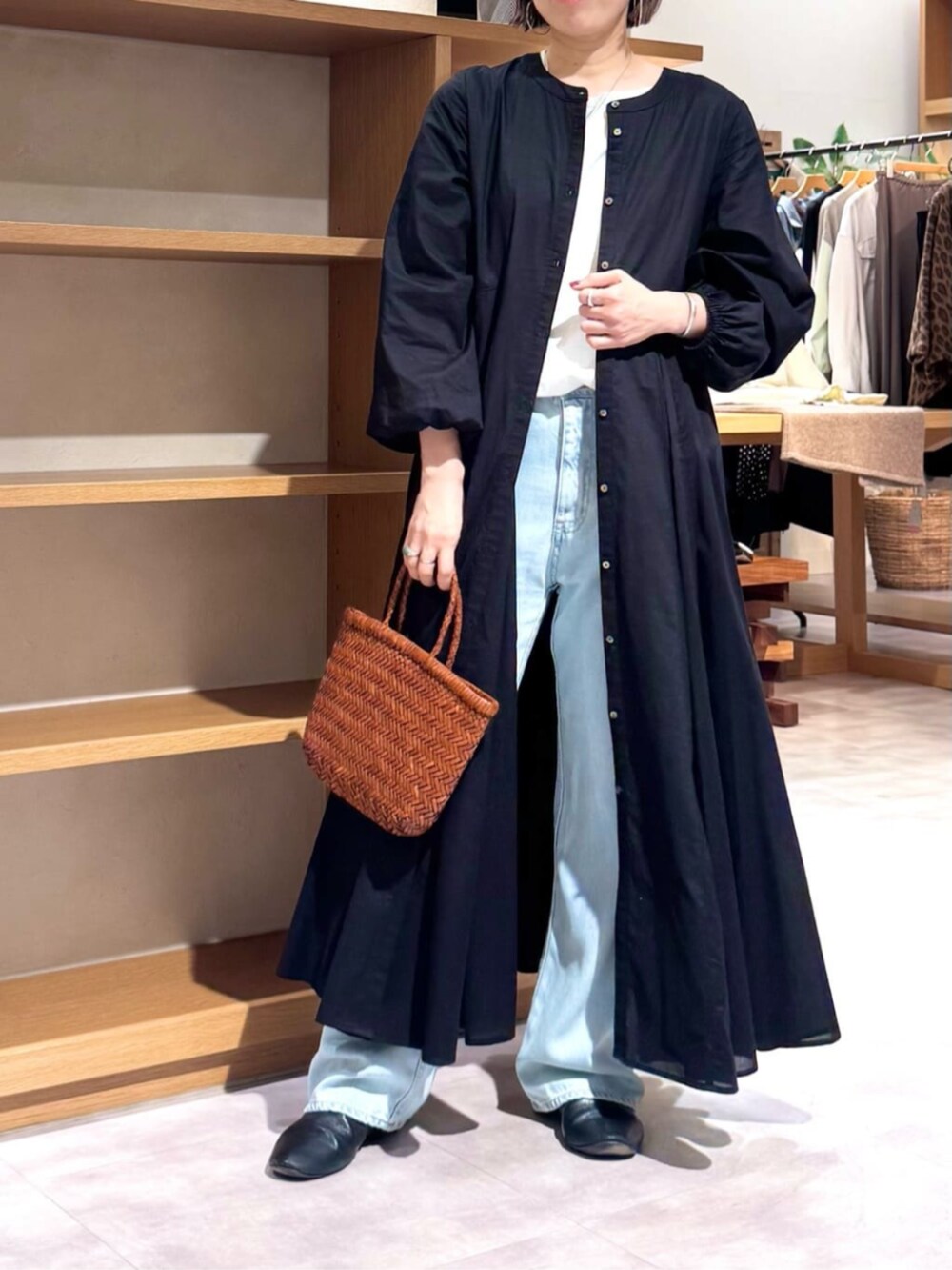 ブルー系のデニムパンツ、イエロー系のトートバッグ、ブラック系のワンピースを着用したレディースの冬コーディネートの4枚目の写真