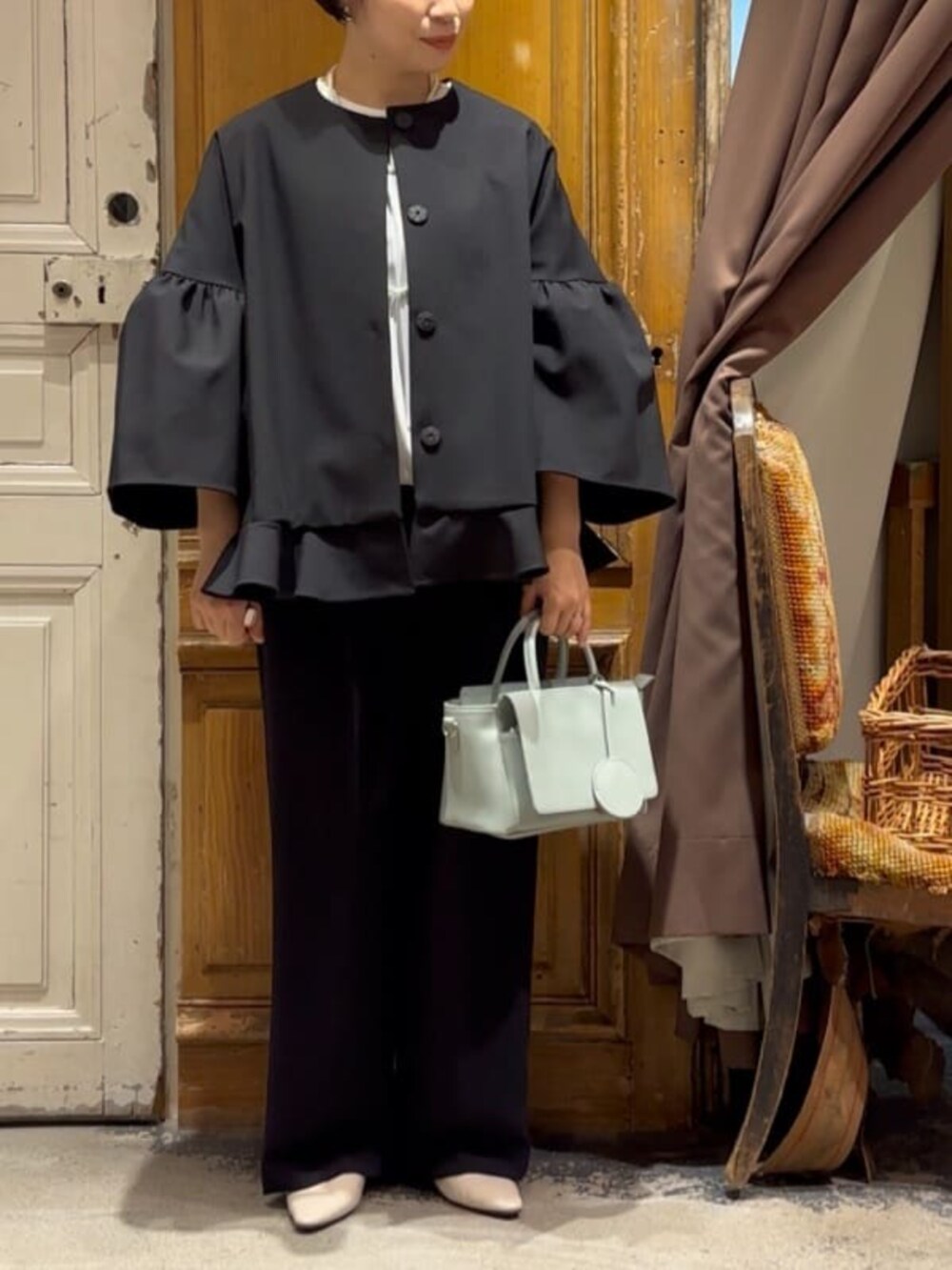 グリーン系のハンドバッグ、ブラック系のその他アウター、ブラック系のその他パンツを着用したレディースの冬コーディネートの4枚目の写真