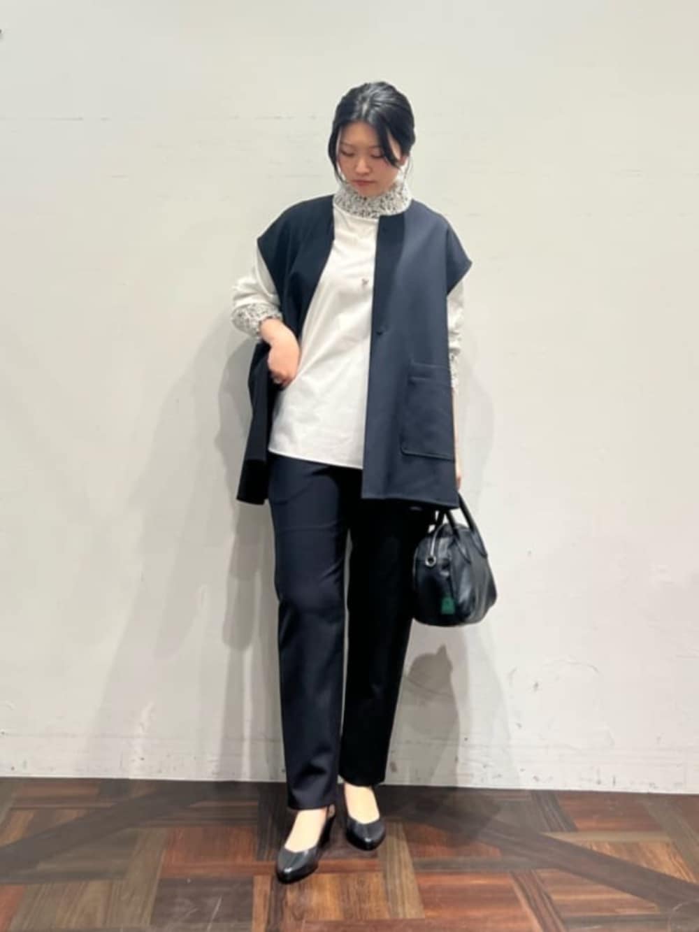 ブラック系のベスト、ブラック系のその他パンツ、ホワイト系のシャツ/ブラウスを着用したレディースの冬コーディネートの2枚目の写真