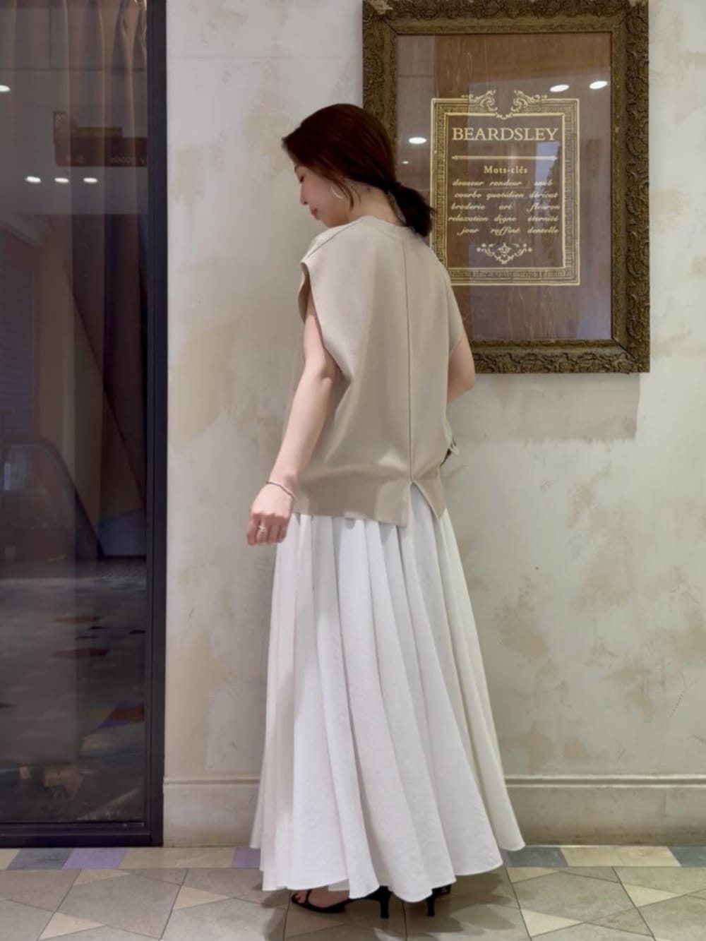 ホワイト系のスカート、ベージュ系のカーディガン/ボレロを着用したレディースの春コーディネートの2枚目の写真