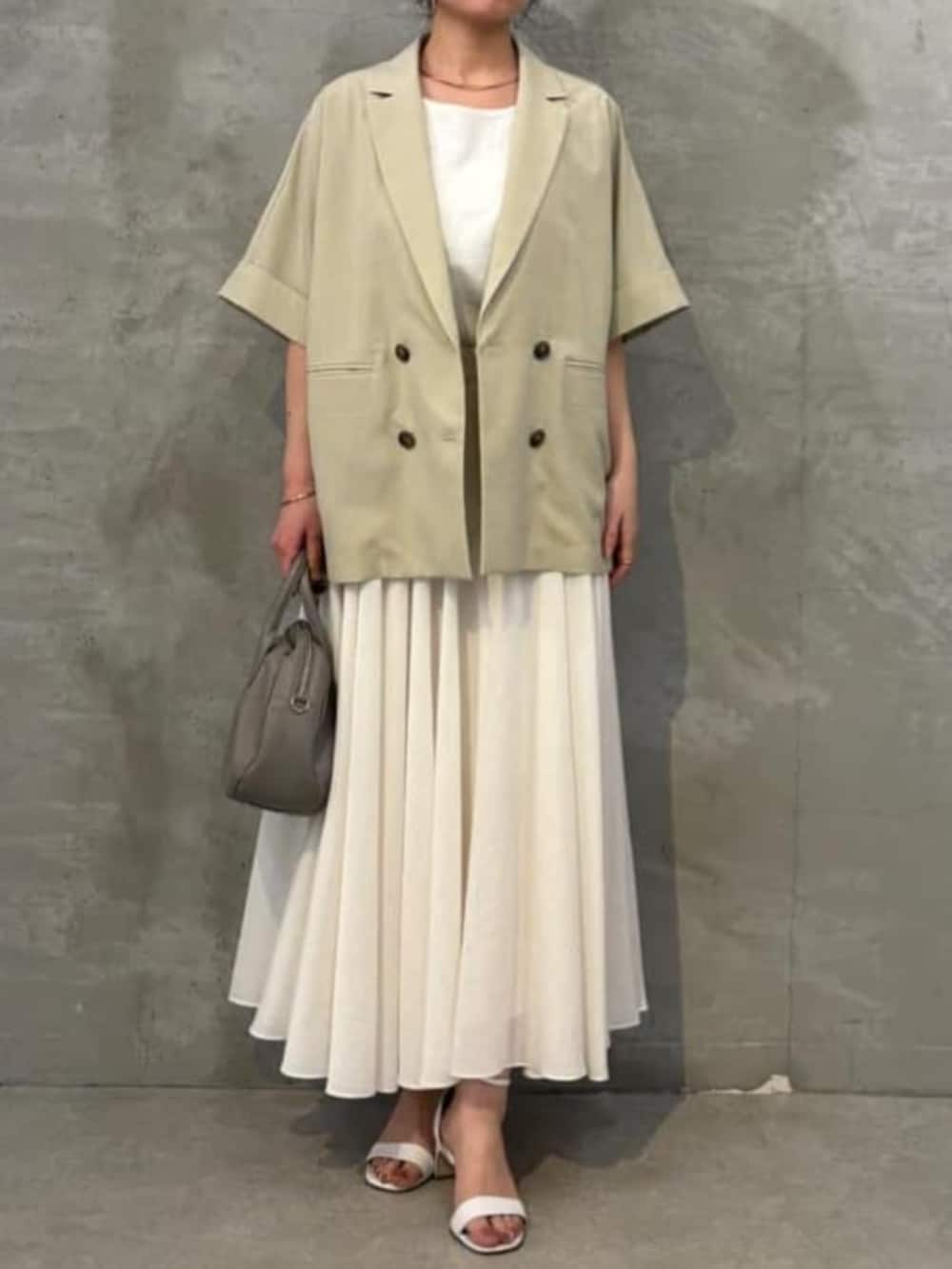 グレー系のボストンバッグ、ホワイト系のキャミソール、ベージュ系のテーラードジャケットを着用したレディースの春コーディネートの3枚目の写真