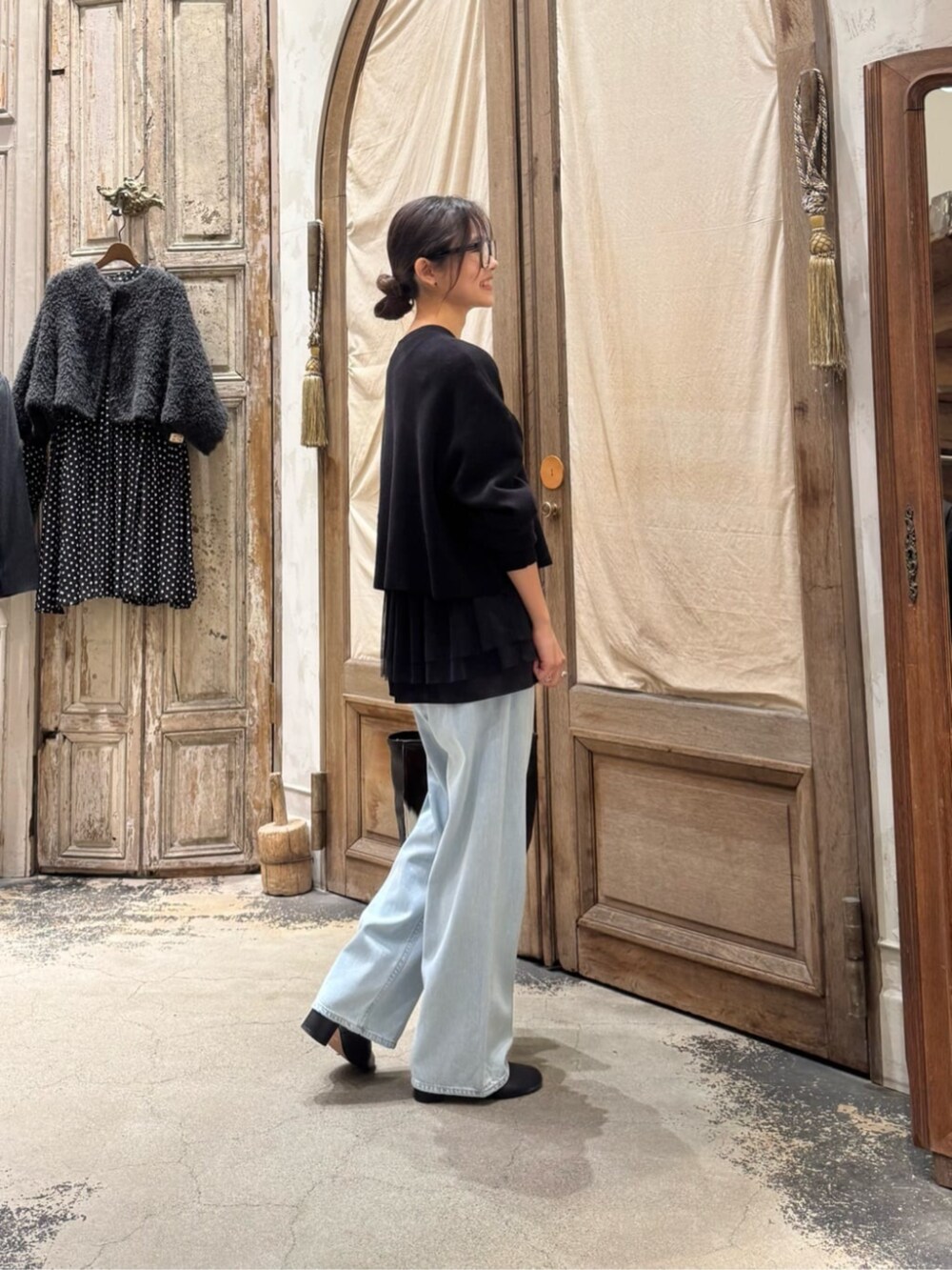 ブルー系のデニムパンツ、ブラウン系のトートバッグ、ブラック系のカーディガン/ボレロを着用したレディースの冬コーディネートの3枚目の写真