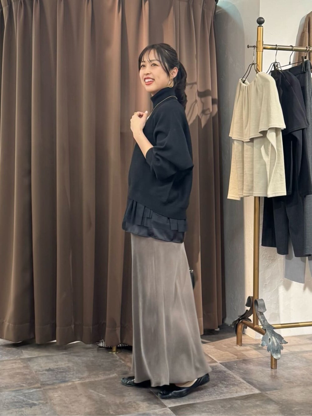 グリーン系のスカート、ブラック系のボストンバッグ、ブラック系のニット/セーターを着用したレディースの冬コーディネートの2枚目の写真