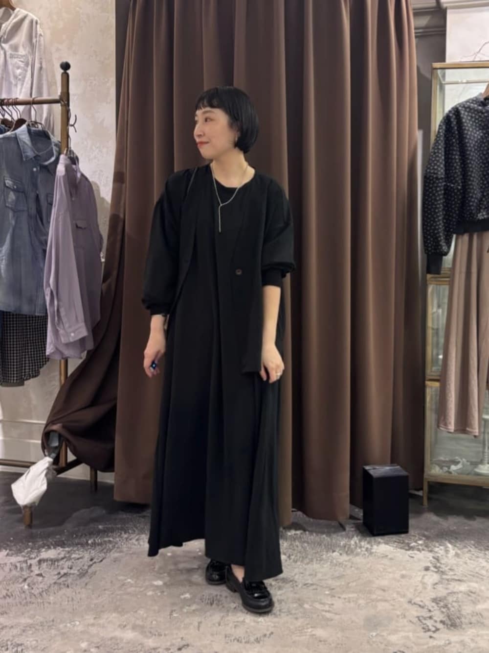 ブラック系のワンピース、ブラック系のその他アウターを着用したレディースの春コーディネートの2枚目の写真