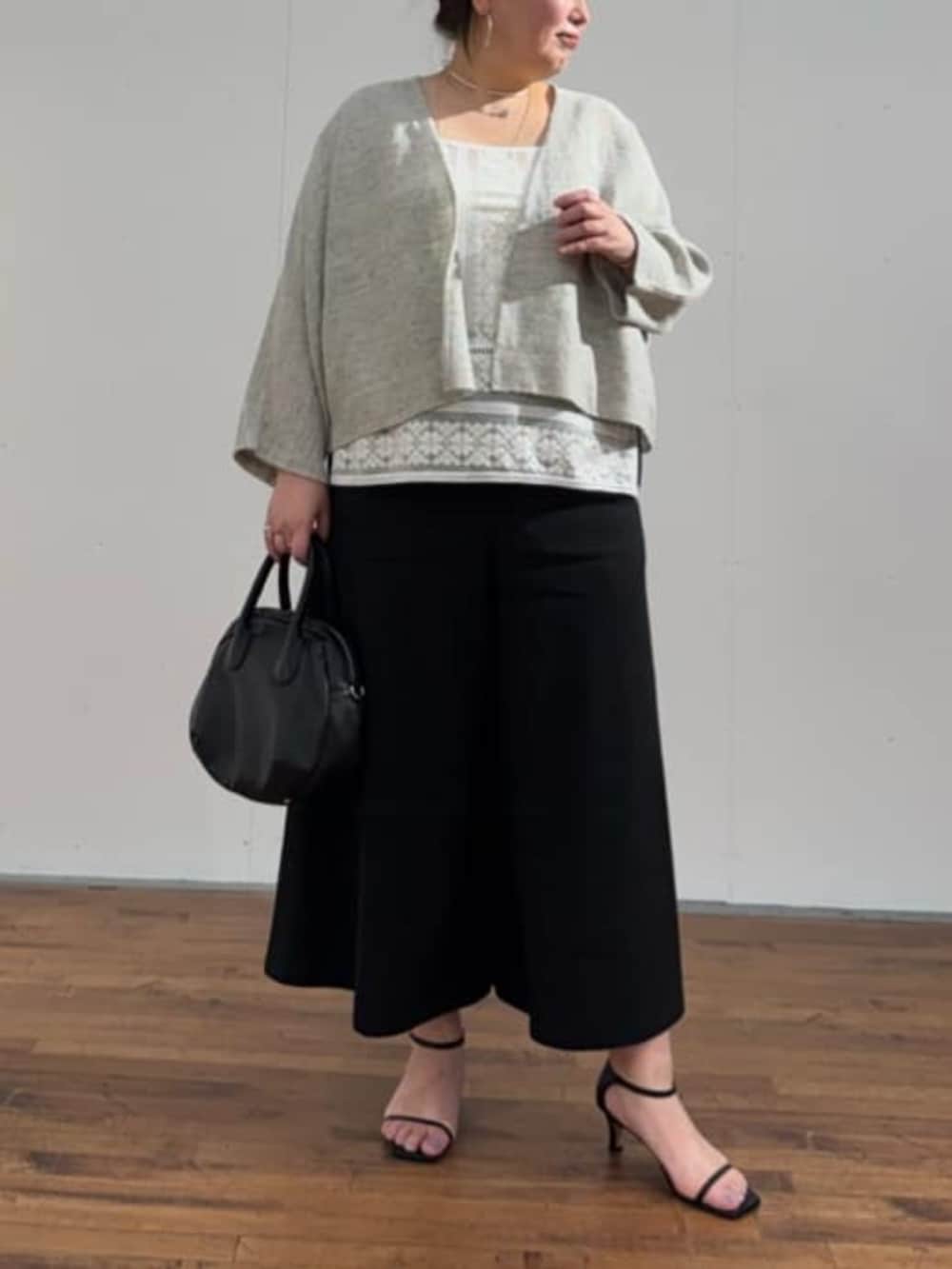 ブラック系のボストンバッグ、ホワイト系のシャツ/ブラウス、グレー系のカーディガン/ボレロを着用したレディースの春コーディネートの7枚目の写真