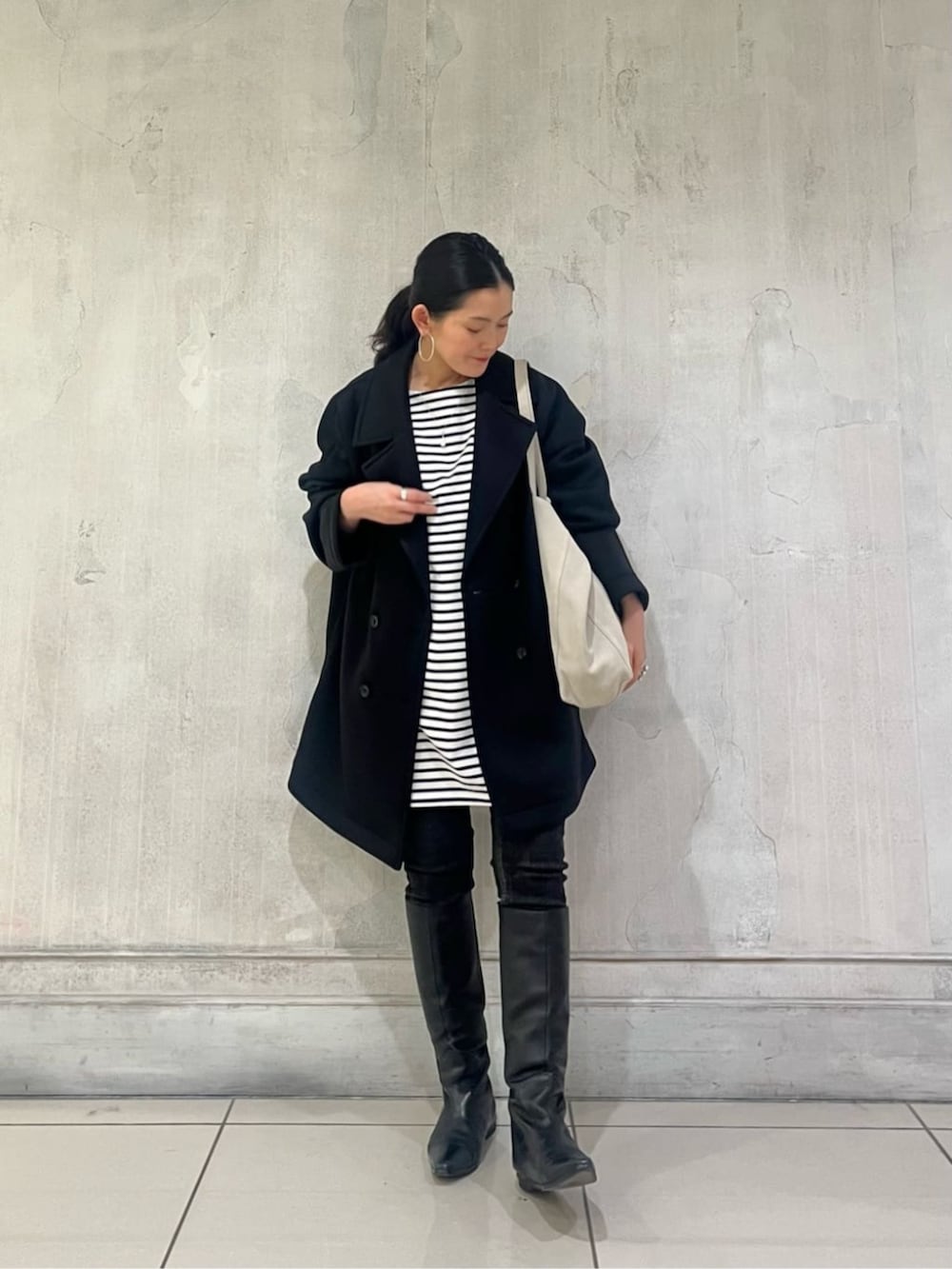 ブルー系のTシャツ/カットソー、ブラック系のデニムパンツ、ブラック系のピーコートを着用したレディースの冬コーディネートの3枚目の写真