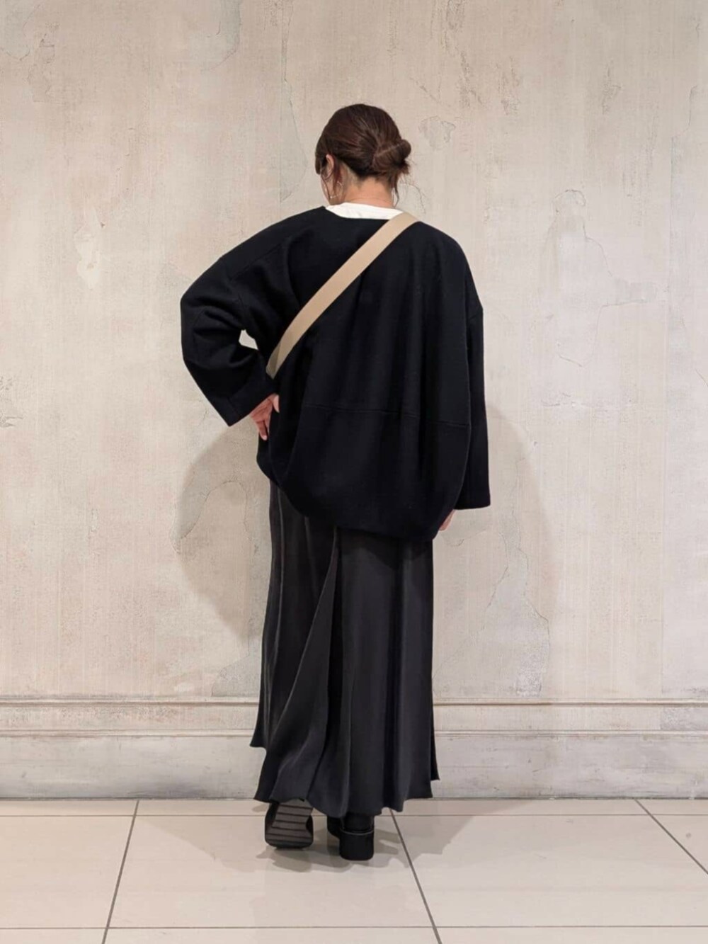 ブラック系のスカート、ブラック系のブーツ、ブルー系のノーカラーコートを着用したレディースの冬コーディネートの3枚目の写真