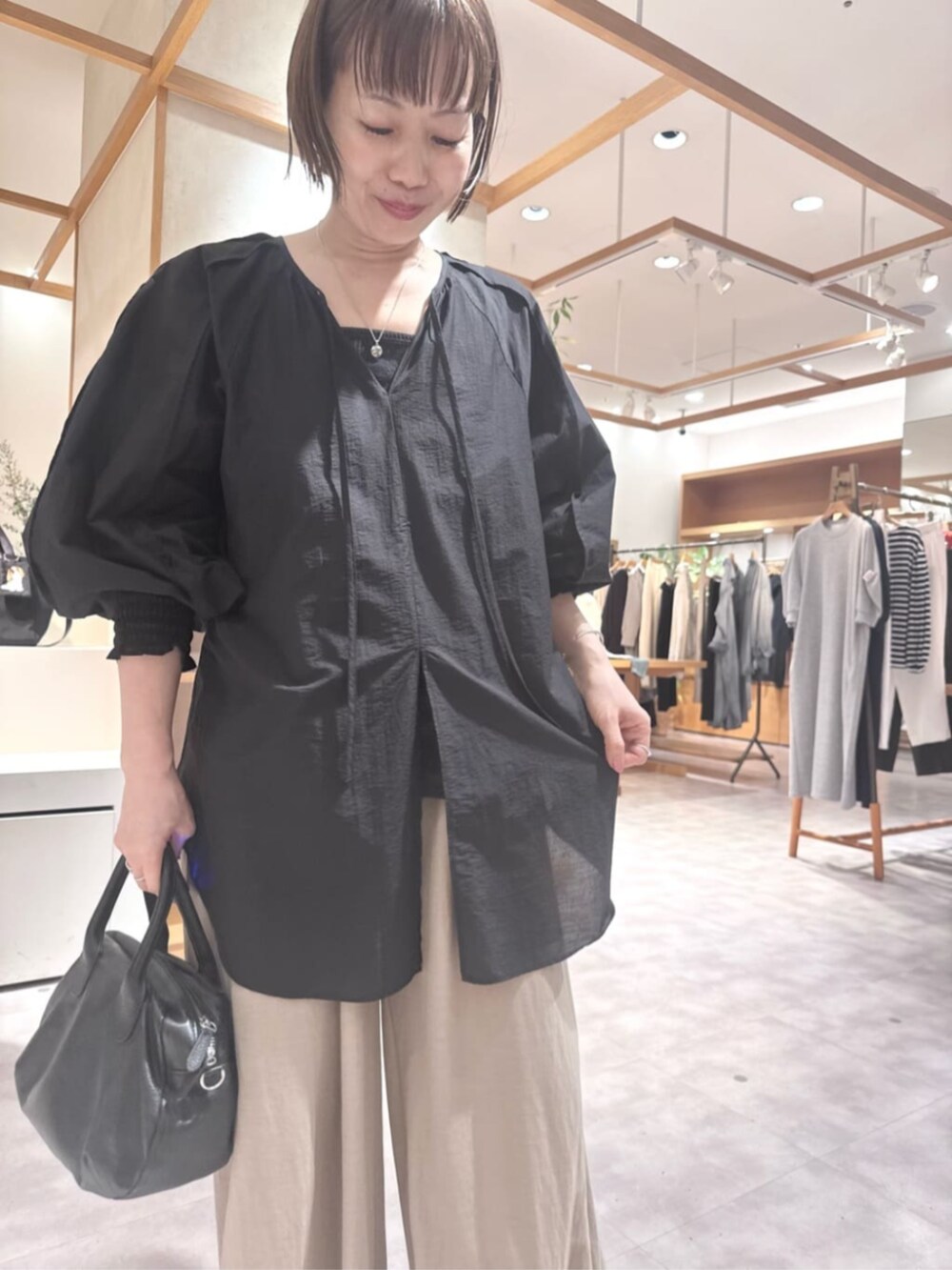 ブラック系のボストンバッグ、ベージュ系のその他パンツ、ブラック系のシャツ/ブラウスを着用したレディースの春コーディネートの8枚目の写真