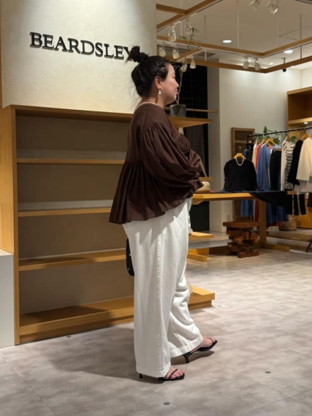 ブラック系のトートバッグ、ホワイト系のデニムパンツ、ブラウン系のシャツ/ブラウスを着用したレディースの冬コーディネートの4枚目の写真