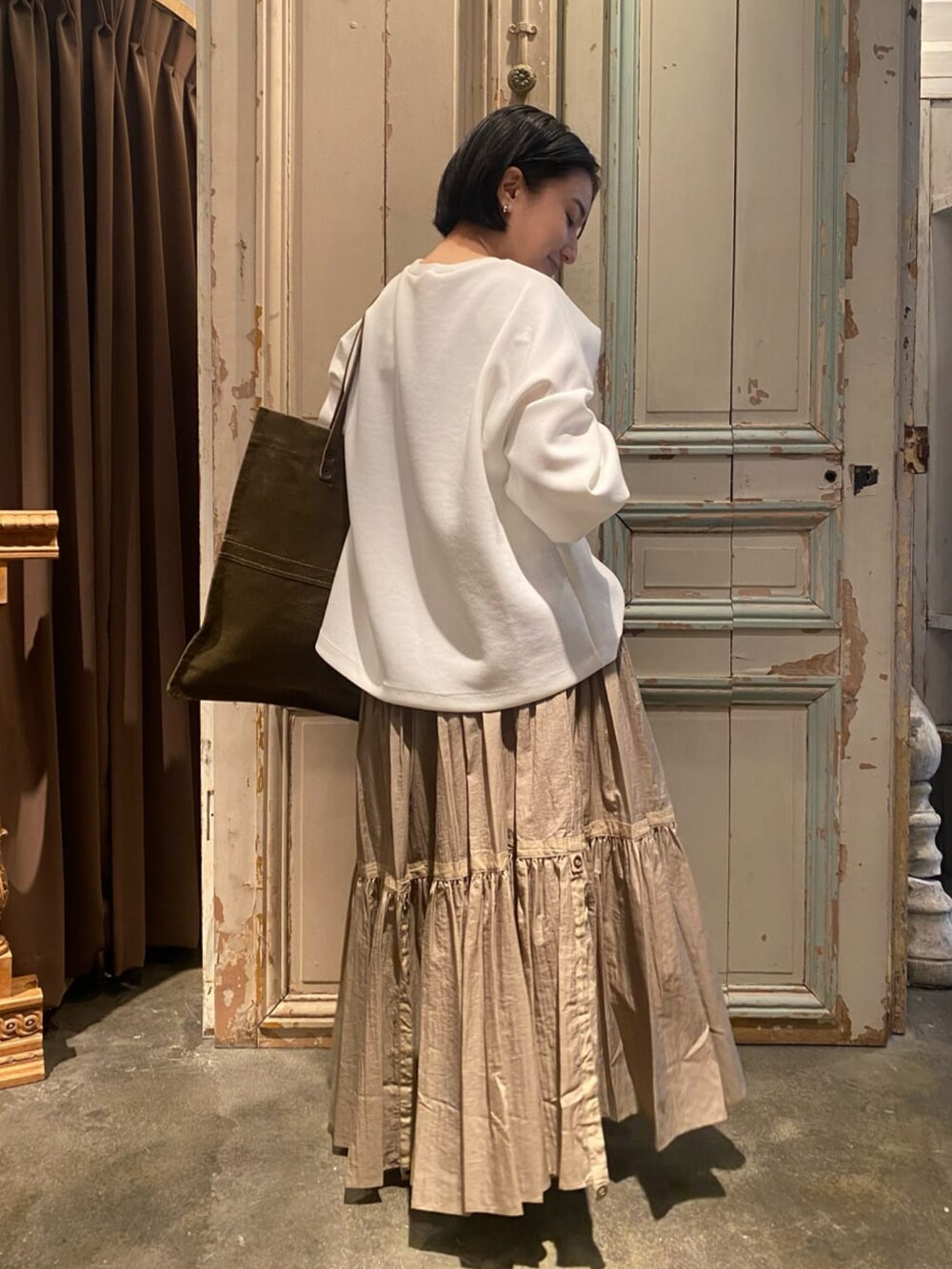 ベージュ系のスカート、ホワイト系のTシャツ/カットソー、グリーン系のトートバッグを着用したレディースの冬コーディネートの3枚目の写真