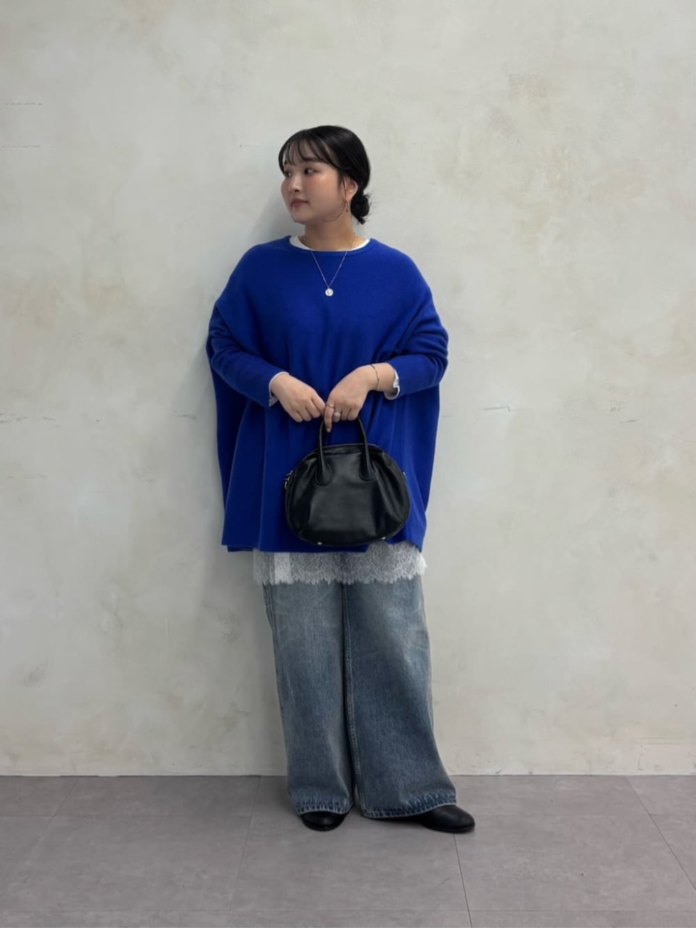 ブラック系のトートバッグ、ブルー系のデニムパンツ、ブラック系のブーツを着用したレディースの秋コーディネートの2枚目の写真