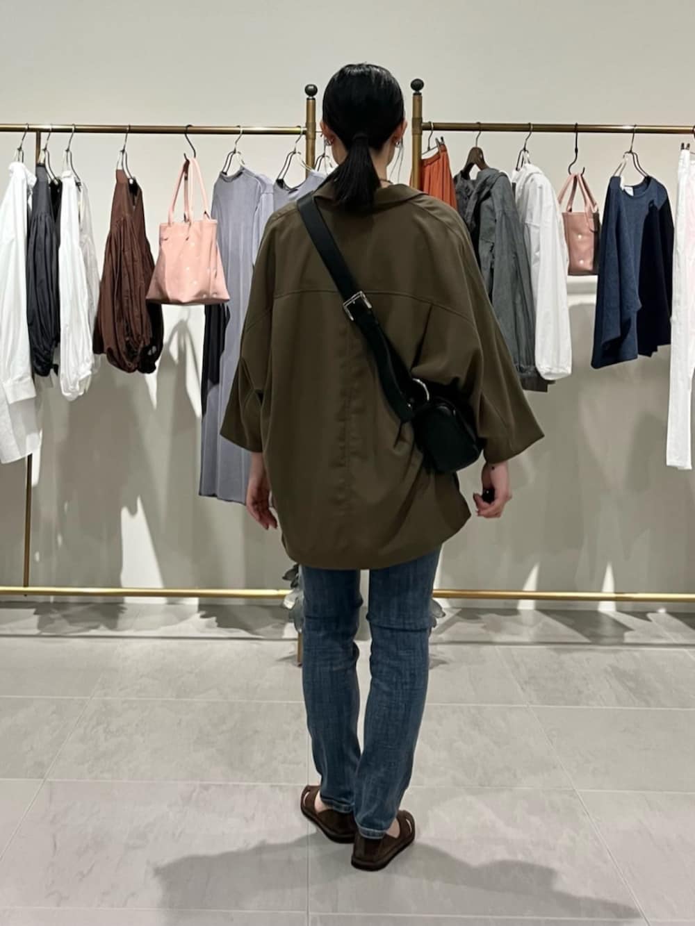 ブルー系のデニムパンツ、ブラック系のショルダーバッグ、ブラウン系のテーラードジャケットを着用したレディースの春コーディネートの2枚目の写真