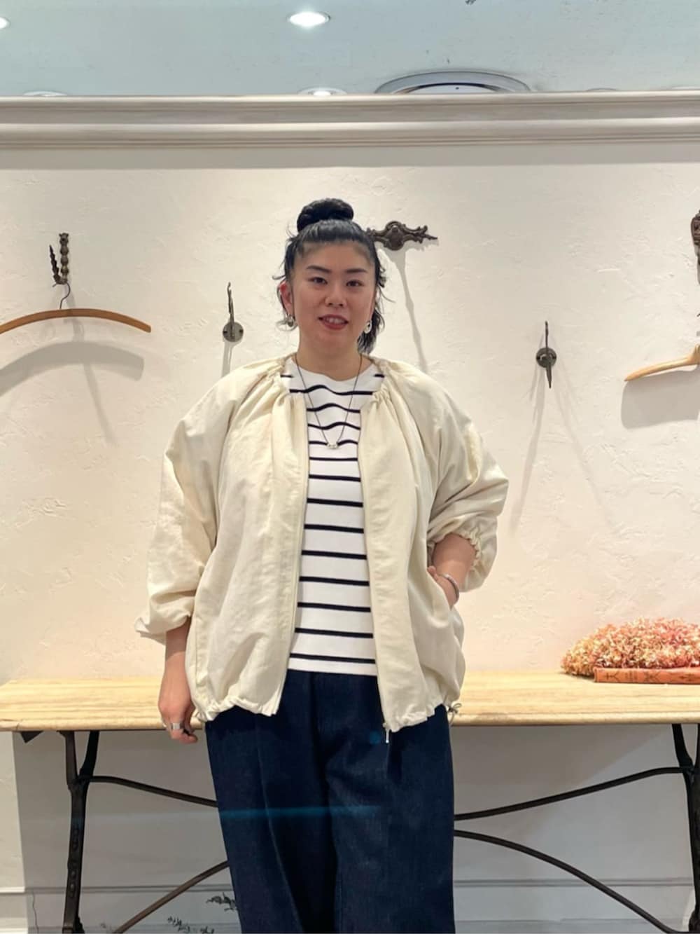 ホワイト系のノーカラージャケット、ホワイト系のニット/セーター、ブルー系のデニムパンツを着用したレディースの冬コーディネートの5枚目の写真