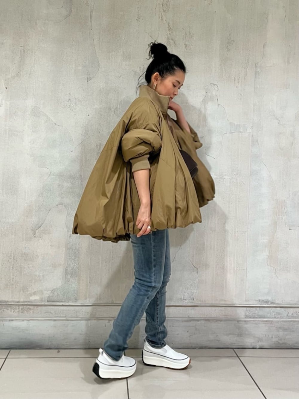 ホワイト系のスニーカー、ブルー系のデニムパンツ、イエロー系のその他アウターを着用したレディースの冬コーディネートの6枚目の写真