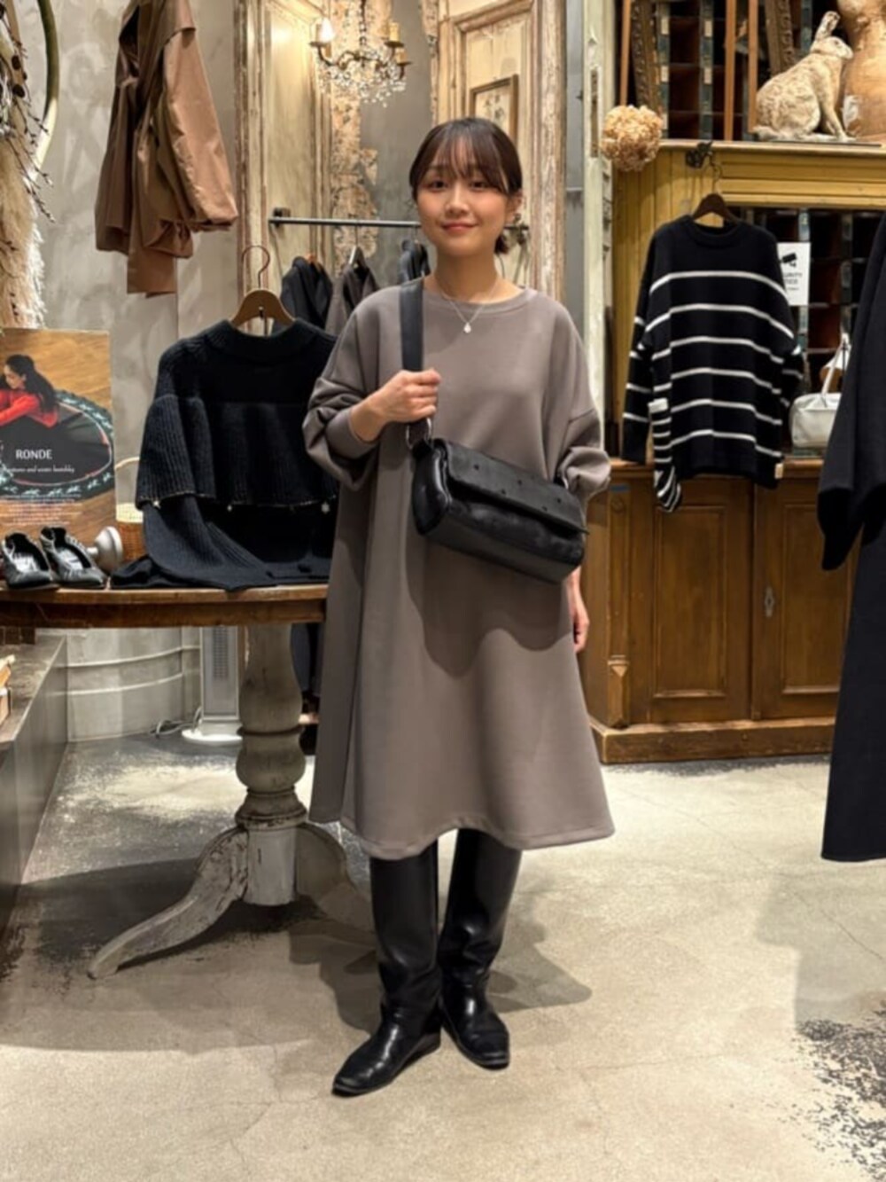 ブラウン系のワンピース、ブラック系のショルダーバッグ、シルバー系のネックレスを着用したレディースの冬コーディネートの2枚目の写真