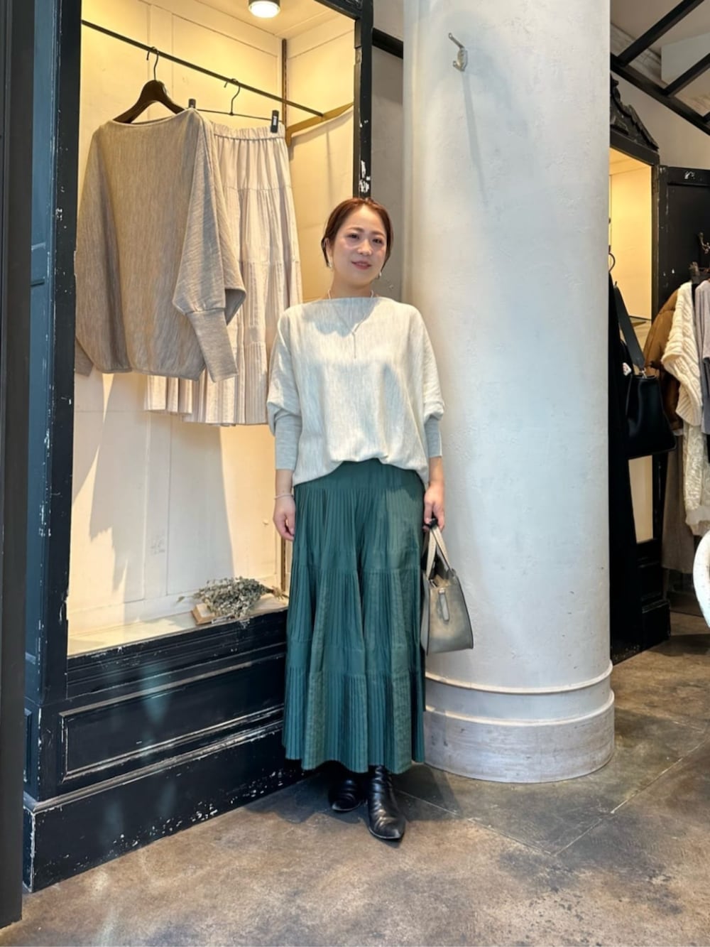 グリーン系のスカート、グレー系のニット/セーター、ブラック系のダウンジャケット/コートを着用したレディースの冬コーディネートの5枚目の写真