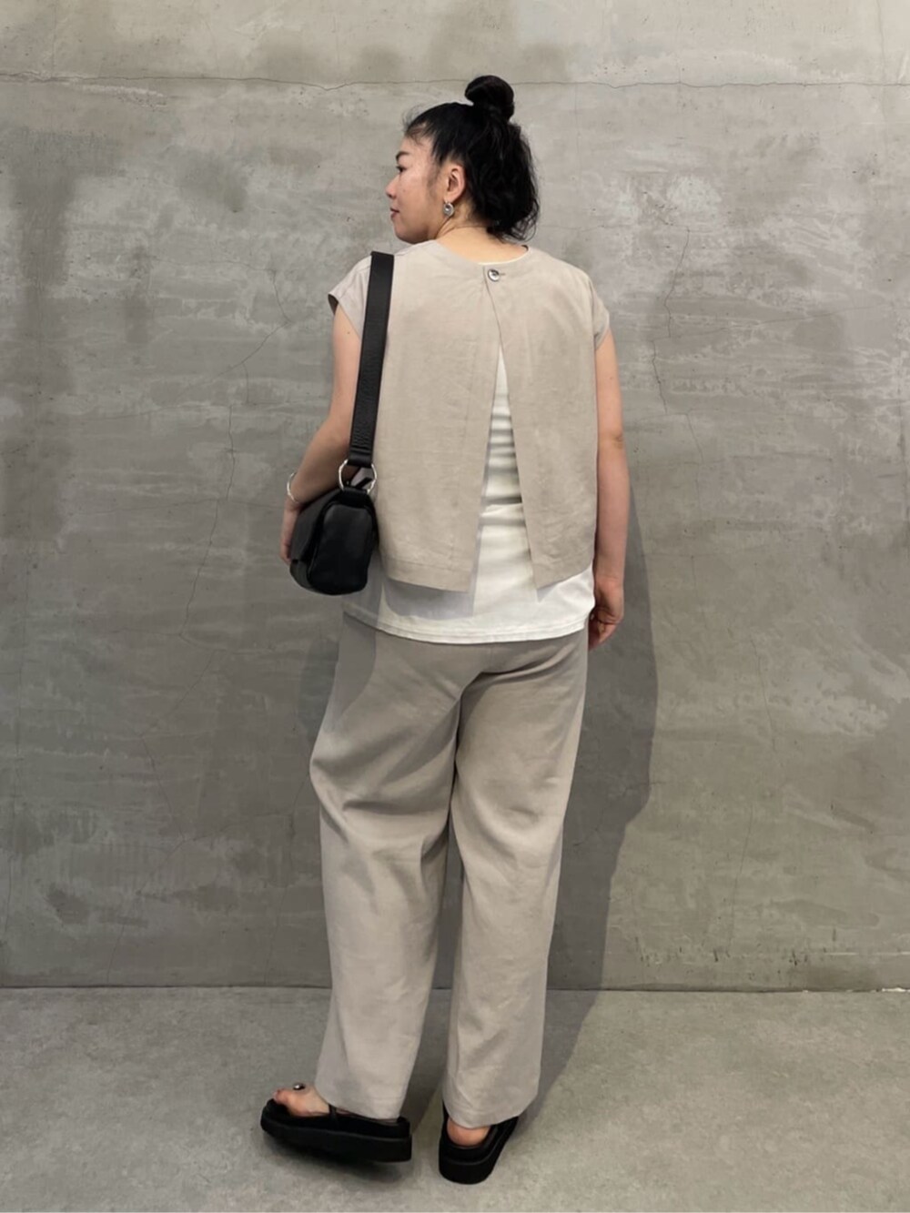 ホワイト系のタンクトップ、ブラック系のショルダーバッグ、ブラック系のサンダルを着用したレディースの春コーディネートの4枚目の写真