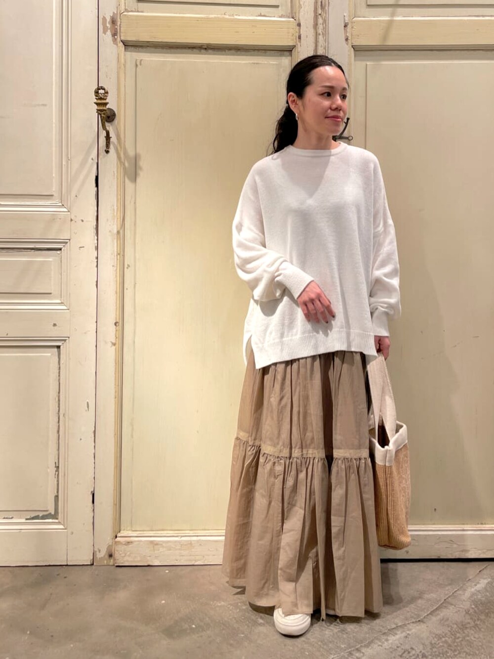 ベージュ系のスカート、ホワイト系のトートバッグ、ホワイト系のニット/セーターを着用したレディースの冬コーディネートの2枚目の写真