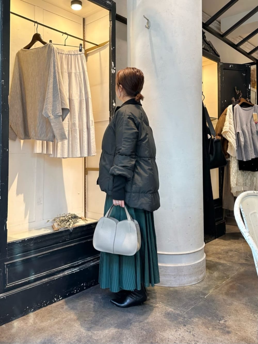 グリーン系のスカート、グレー系のニット/セーター、ブラック系のダウンジャケット/コートを着用したレディースの冬コーディネートの2枚目の写真