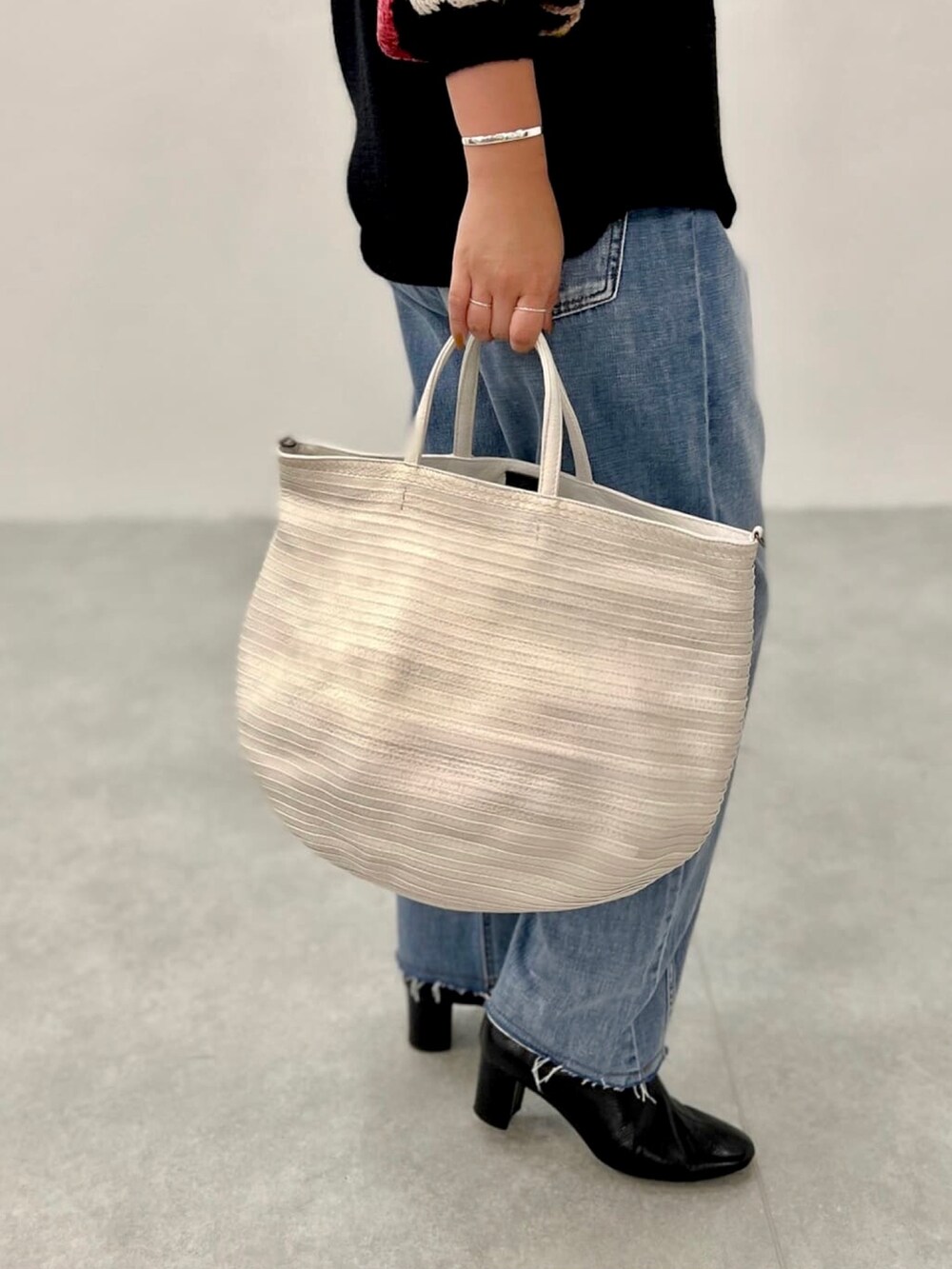 ブラック系のニット/セーター、ブルー系のデニムパンツを着用したレディースの夏コーディネートの5枚目の写真