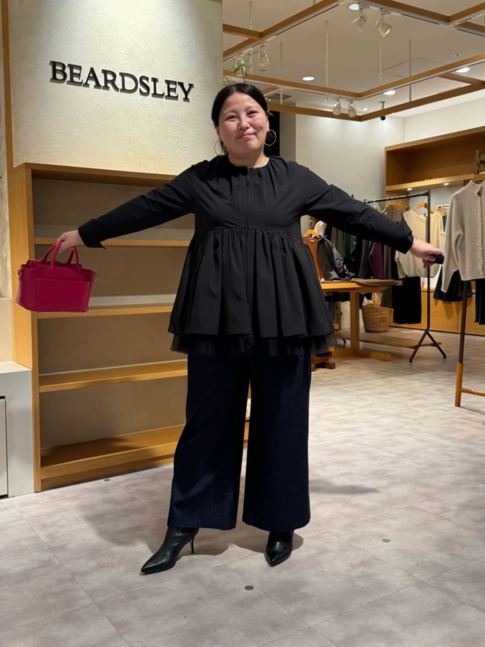 ピンク系のハンドバッグ、ブラック系のブーツ、ブラック系のブルゾンを着用したレディースの冬コーディネートの7枚目の写真