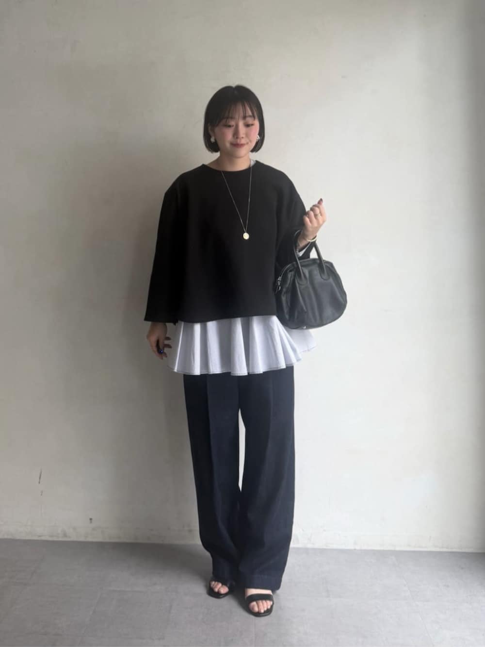 ブラック系のボストンバッグ、ブラック系のTシャツ/カットソー、ブルー系のデニムパンツを着用したレディースの冬コーディネートの2枚目の写真