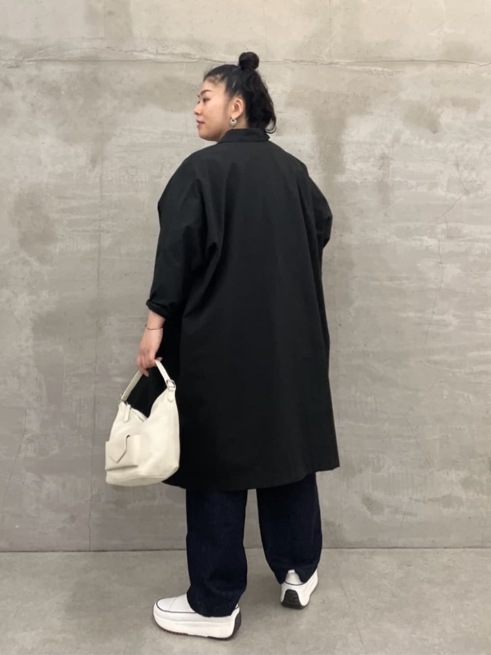 ホワイト系のトートバッグ、ブルー系のデニムパンツ、ブラック系のその他アウターを着用したレディースの冬コーディネートの3枚目の写真