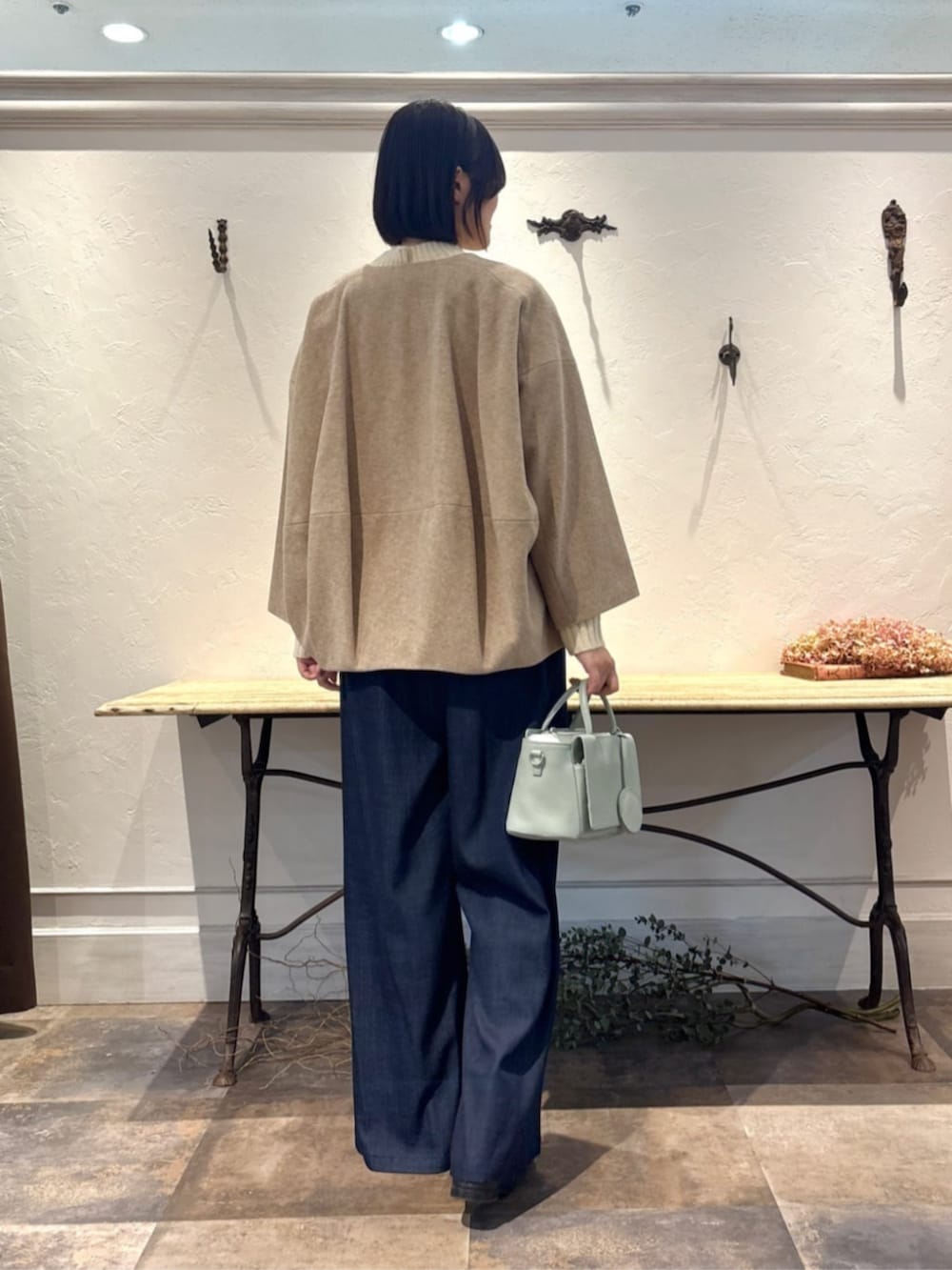 ブルー系のその他パンツ、グリーン系のハンドバッグ、ホワイト系のニット/セーターを着用したレディースの冬コーディネートの3枚目の写真