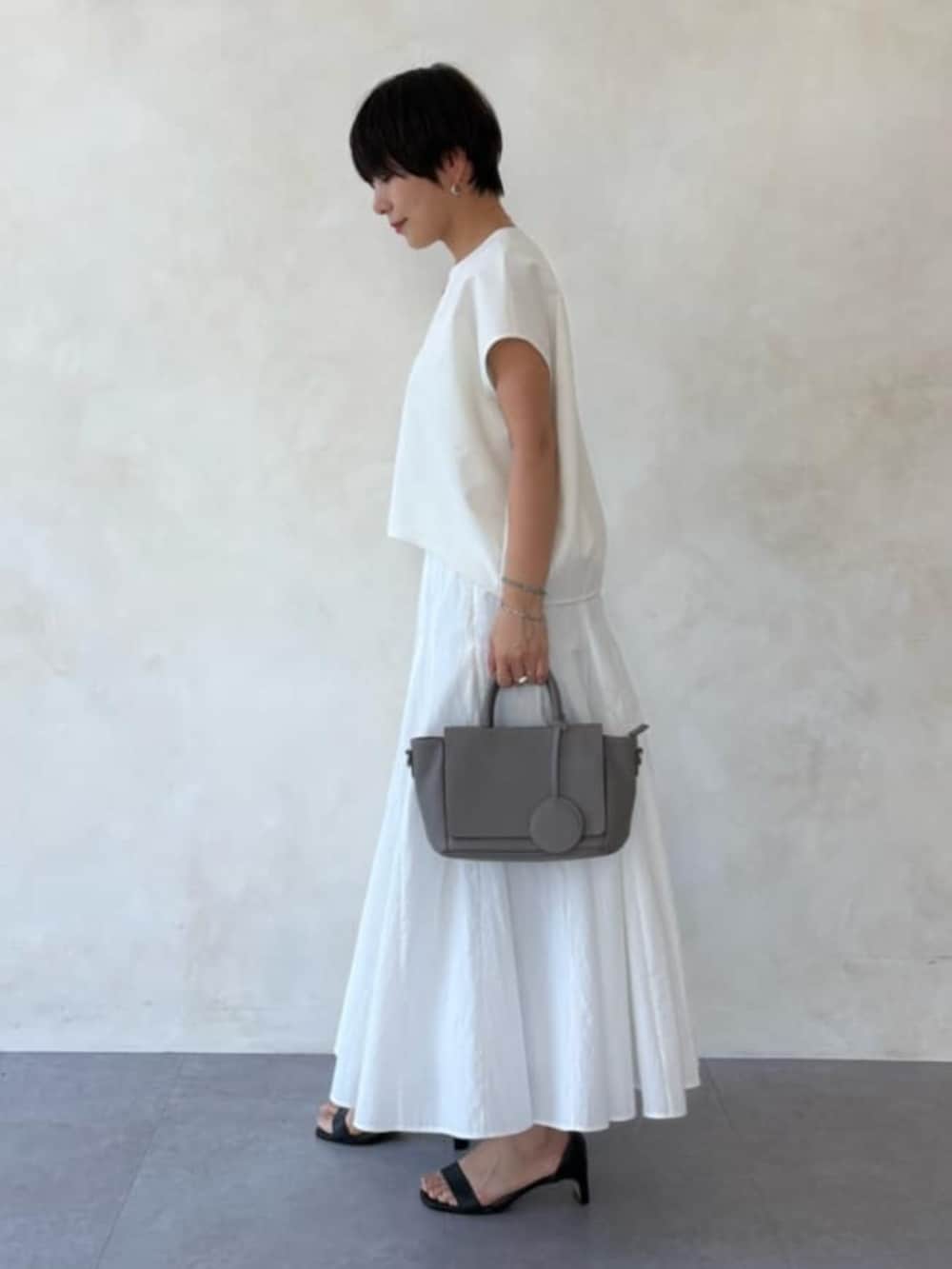 グレー系のハンドバッグ、ホワイト系のスカート、ホワイト系のシャツ/ブラウスを着用したレディースの春コーディネートの2枚目の写真