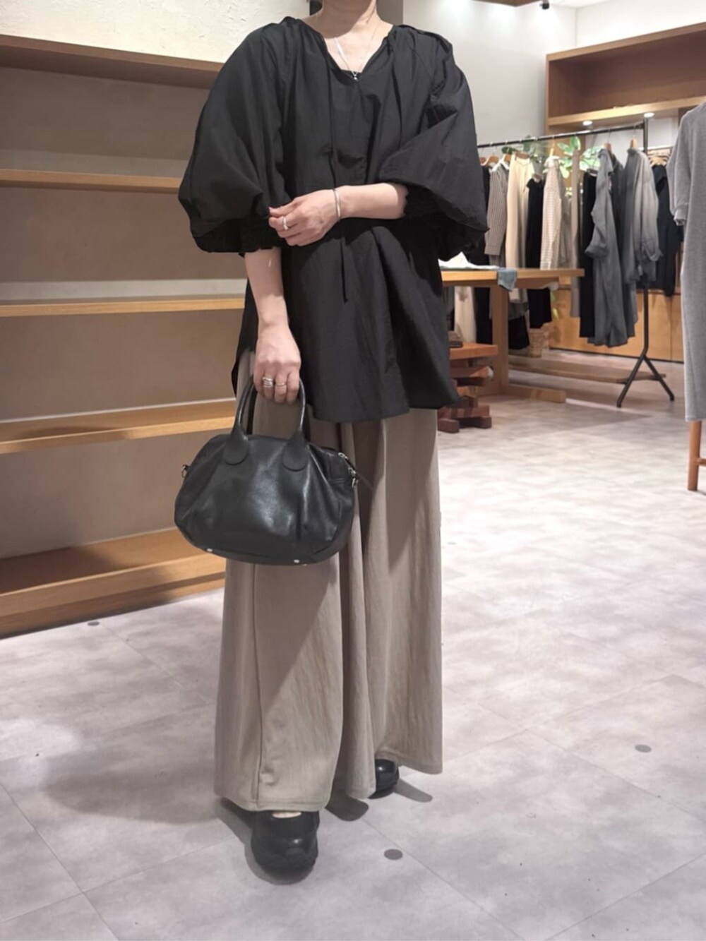 ブラック系のボストンバッグ、ベージュ系のその他パンツ、ブラック系のシャツ/ブラウスを着用したレディースの春コーディネートの5枚目の写真
