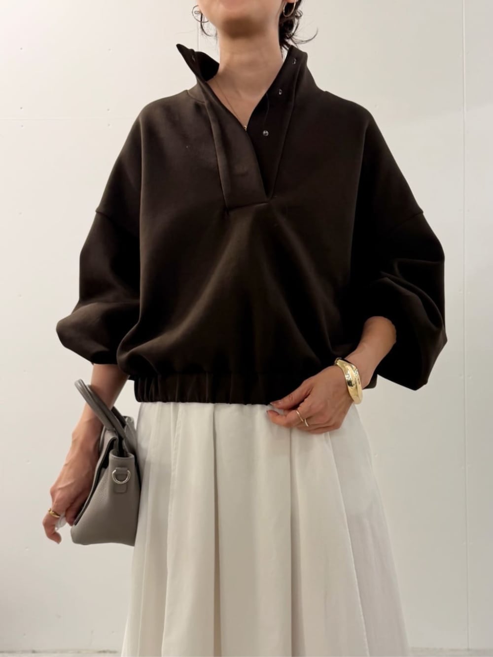 グレー系のハンドバッグ、ホワイト系のスカート、ブラウン系のTシャツ/カットソーを着用したレディースの夏コーディネートの4枚目の写真