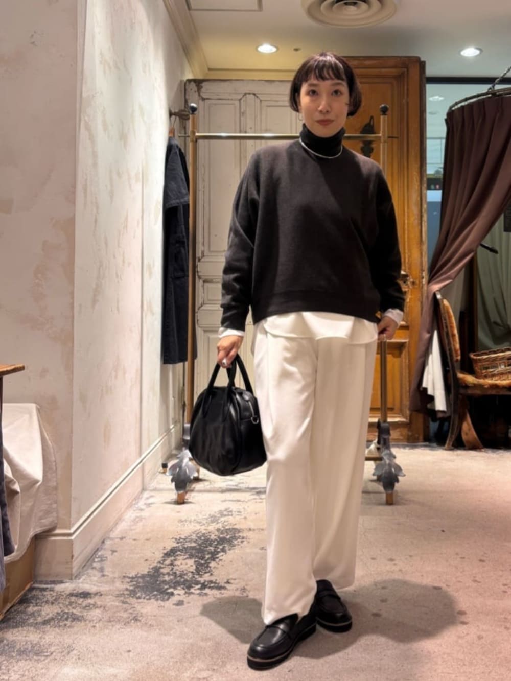 グレー系のニット/セーター、ブラック系のトートバッグ、ホワイト系のその他パンツを着用したレディースの秋コーディネートの2枚目の写真