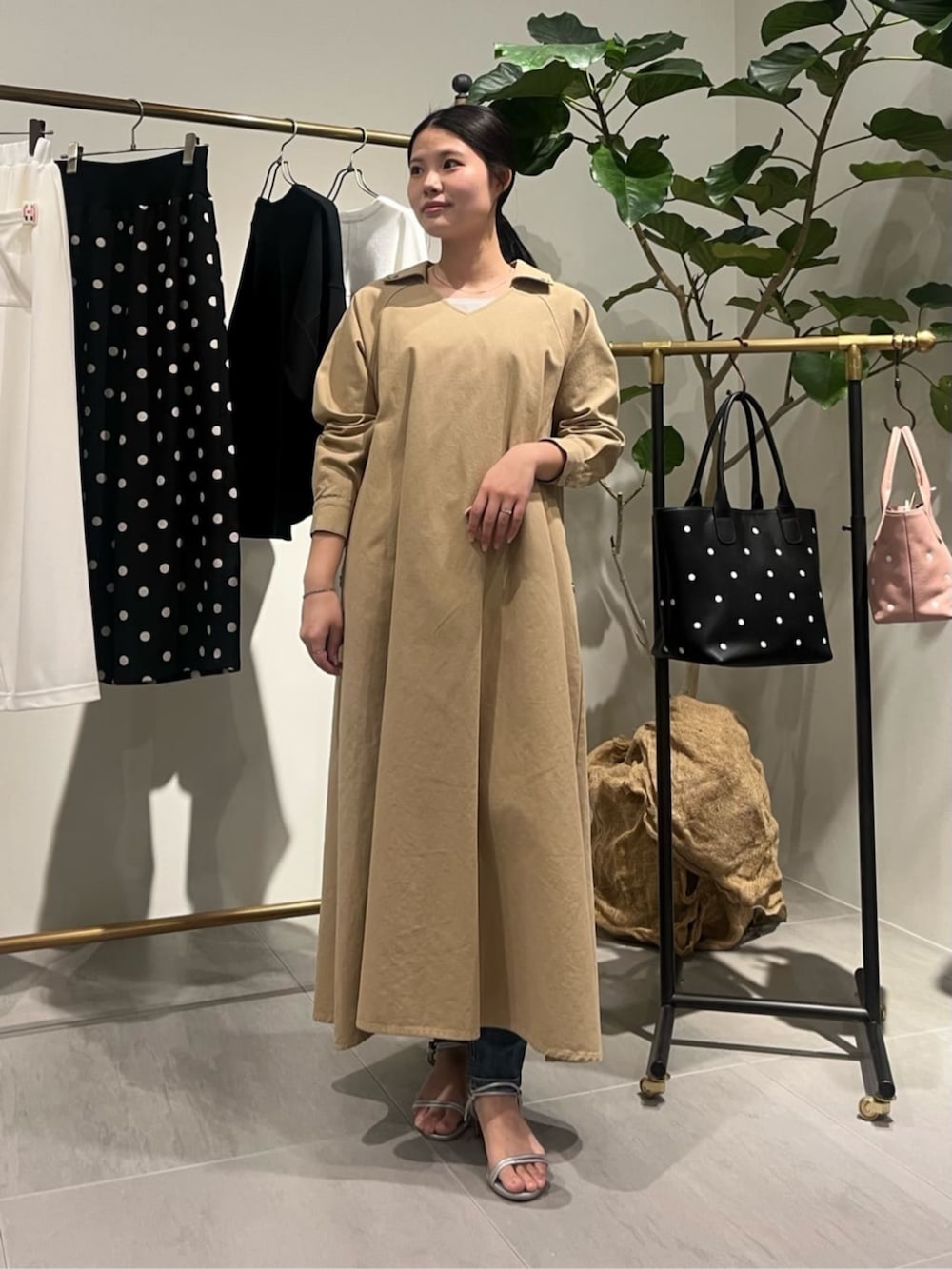 ブラック系のショルダーバッグ、ベージュ系のワンピースを着用したレディースの春コーディネートの3枚目の写真